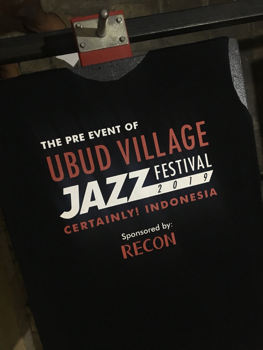 Black festival t-shirt with a multicolour screen print, laid flat.